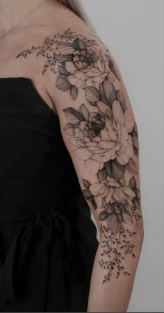 a woman wearing a black dress with flowers on her arm