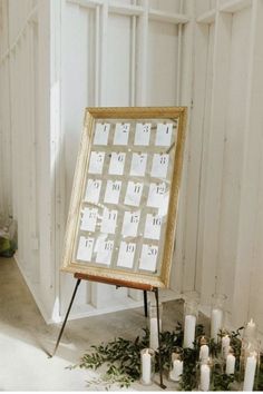 a calendar sitting on top of a table next to candles and greenery in front of a white wall