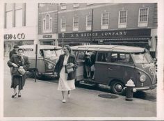 an old black and white photo of people walking down the street in front of buses