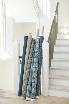 a bunch of different colored rugs sitting on the floor in front of some stairs