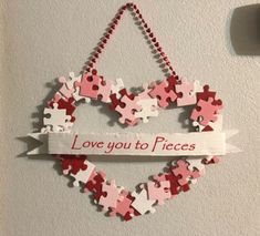 a heart shaped puzzle hanging on the wall with a ribbon that says love you to pieces