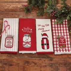 four christmas kitchen towels on top of a wooden table