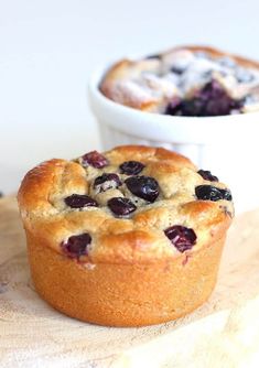 two blueberry muffins sitting on top of a wooden cutting board