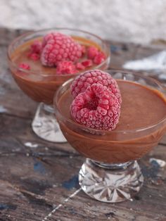 two glasses filled with chocolate pudding and raspberries