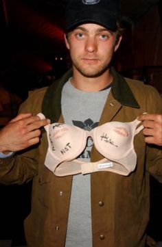 a man is holding two bras in front of his face while wearing a hat