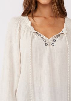 A classic off-white boho blouse with embroidered detail throughout. Embroidered detail Relaxed fit Long raglan sleeve Single-button wrist closure Split v-neckline with tassel ties Smocked neckline Bohemian blouse Classic bohemian details add a cool, effortless touch to this essential fall blouse. Featuring intricately embroidered details and tassel neckties. Perfect for fall and beyond, we love to tuck it into our favorite vintage denim. Model is 5'9, wearing a size S.Style: I-15193W-RRR White Boho Blouse, Blouse With Long Sleeves, Bohemian Blouse, Fall Blouse, Bohemian Blouses, Bohemian Tops, Boho Blouse, Fall Essentials, Embroidered Details