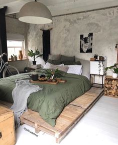 a bedroom with a bed made out of wooden pallets and lots of greenery