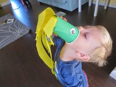 a young boy with a green and yellow cup on his head looking at the camera