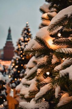 a christmas tree is covered with snow and lite up by street lights in the background