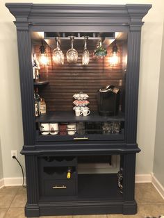 an entertainment center with wine glasses and liquor bottles on the top shelf in front of it