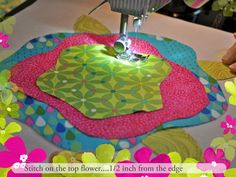 a person using a sewing machine to sew on a piece of fabric with flowers in the background