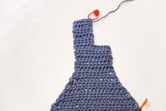 a crocheted blue piece of cloth with an orange string attached to the end