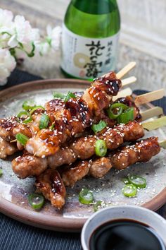 chicken skewers with sesame seeds and green onions on a plate