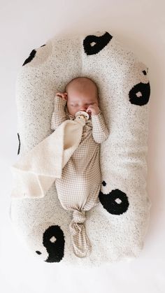 a baby wrapped in a blanket is laying on top of a black and white pillow