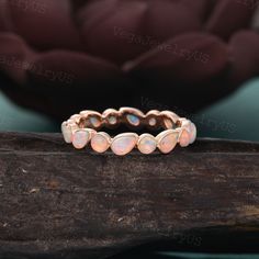 an opalite ring sits on top of a piece of wood with a flower in the background