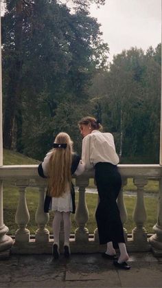 two women standing next to each other on a balcony