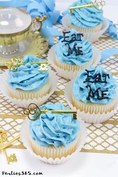 four cupcakes with blue frosting and the words eat me on them