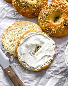 bagels with cream cheese and poppy seed sprinkles on white parchment paper