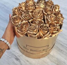 a hand holding a gold box filled with roses