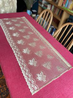 a pink table cloth with white lace on it in front of some bookshelves