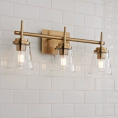 three light bathroom fixture with clear glass shades on white tile backsplash wallpaper