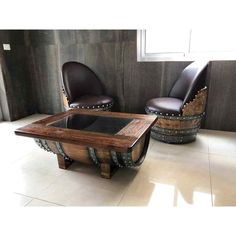 two leather chairs sitting next to each other in front of a table with a glass top