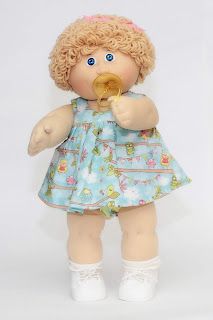 a doll with blonde hair and blue dress holding a spoon in her hand while standing against a white background