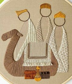 an embroidery project with three people and a camel in the middle, on a beige background