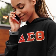 a woman talking on a cell phone while wearing a black hoodie with the letters ao on it