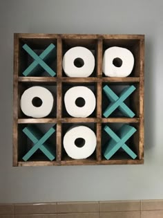 several rolls of toilet paper are arranged in a wooden box on the wall above a sink