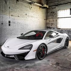 the white sports car is parked in an empty room with exposed brick walls and large windows