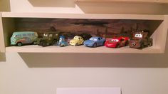 the toy cars are lined up on the shelf