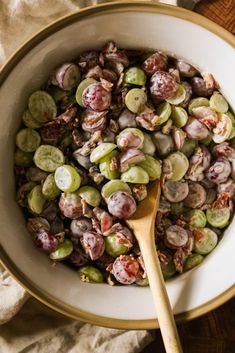 a white bowl filled with brussel sprouts next to a wooden spoon