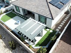 an aerial view of a house with solar panels on the roof and green lawning