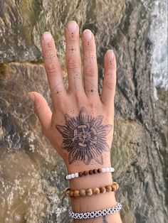 a woman's hand with a sun tattoo on it and bracelets around her wrist