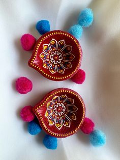 two red and blue pom poms sitting on top of a white cloth covered surface