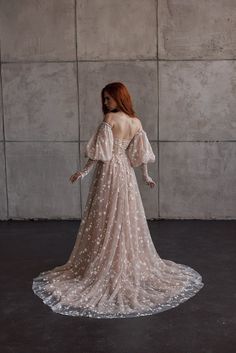 the back of a woman in a wedding dress with long sleeves and stars on it