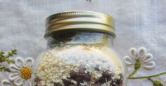 a jar filled with lots of food on top of a white table cloth next to flowers