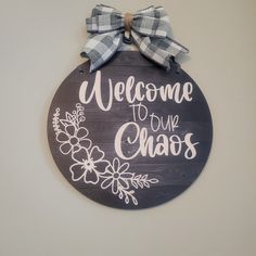 a welcome to our chaos sign with a bow on the front and back of it