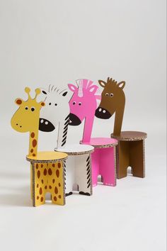 three giraffe and zebra chairs sitting next to each other on a white surface