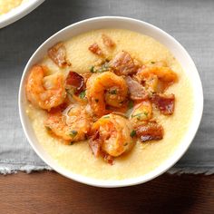 two bowls of soup with shrimp, bacon and grits in them on a table