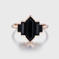 a gold ring with an black stone on the front and side, set against a white background