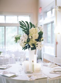 a table with white flowers and candles on it is set for a formal function in the dining room