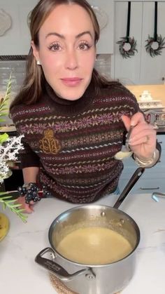 a woman in a sweater stirring a pot of soup