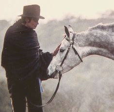 a man in a hat is petting a horse