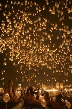 people are sitting on the ground and floating lanterns in the sky with words happy birthday