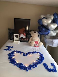 a teddy bear sitting on top of a table with blue and white streamers in the shape of a heart