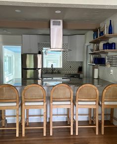 four chairs are lined up in front of the kitchen counter