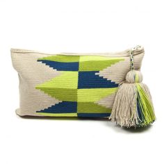 a green and blue pillow with tassels on the front, sitting next to a white background