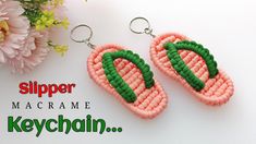 a pair of pink and green earrings sitting on top of a white table next to flowers